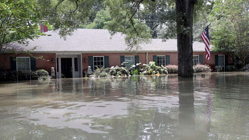 A United States flag hangs outside a flooded home in the aftermath of Hurricane Harvey,...
