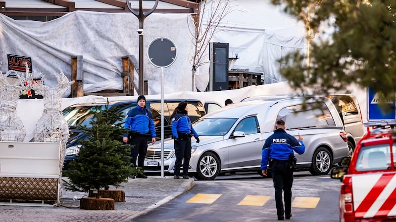 A hearse car drives as police officers inspect the area where a fire broke out at the Le...