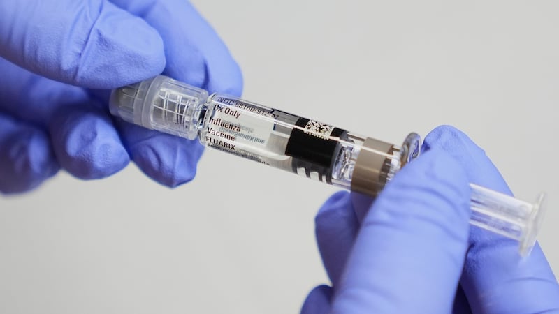 FILE - A certified medical assistant holds a syringe for a flu vaccine at a clinic in Seattle,...